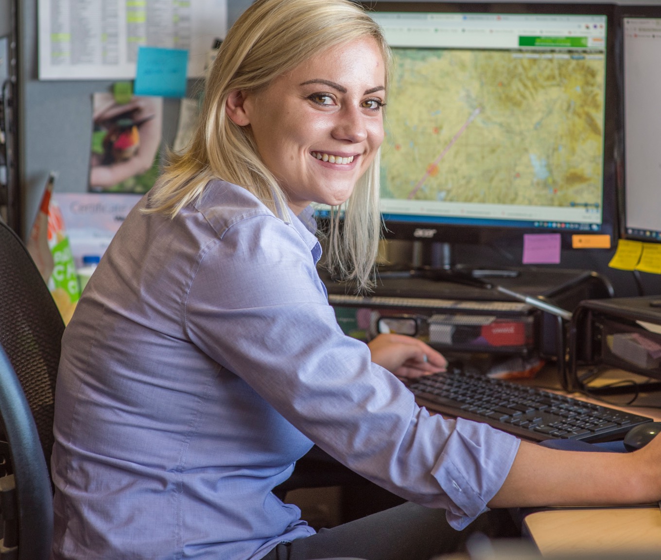 A woman sitting at a desk reviewing a map on a computer screen.