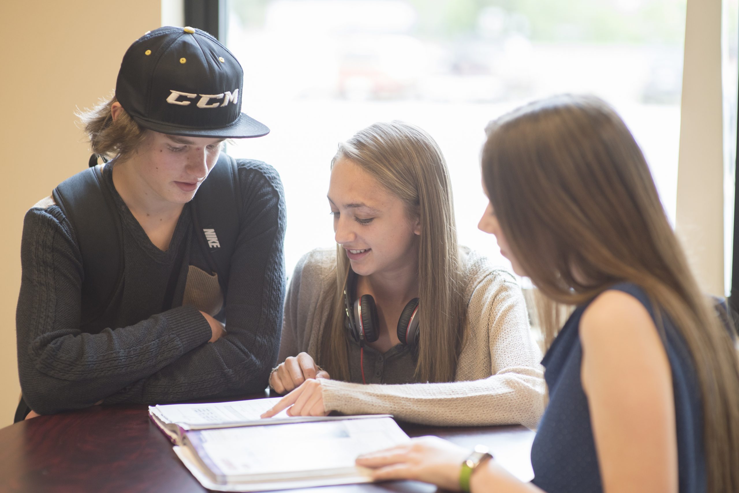 Three students reviewing a textbook together.