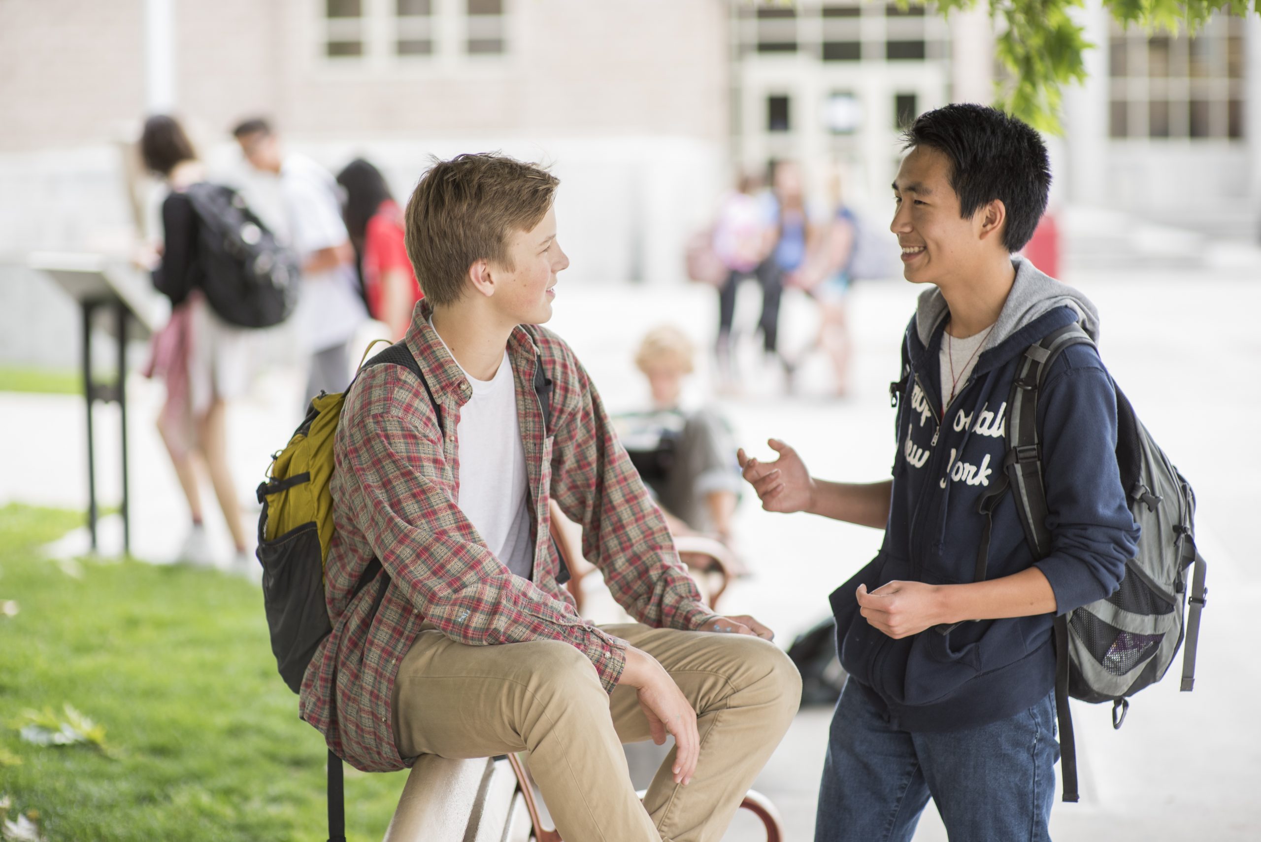 Two male students with backpacks chatting outside on campus.