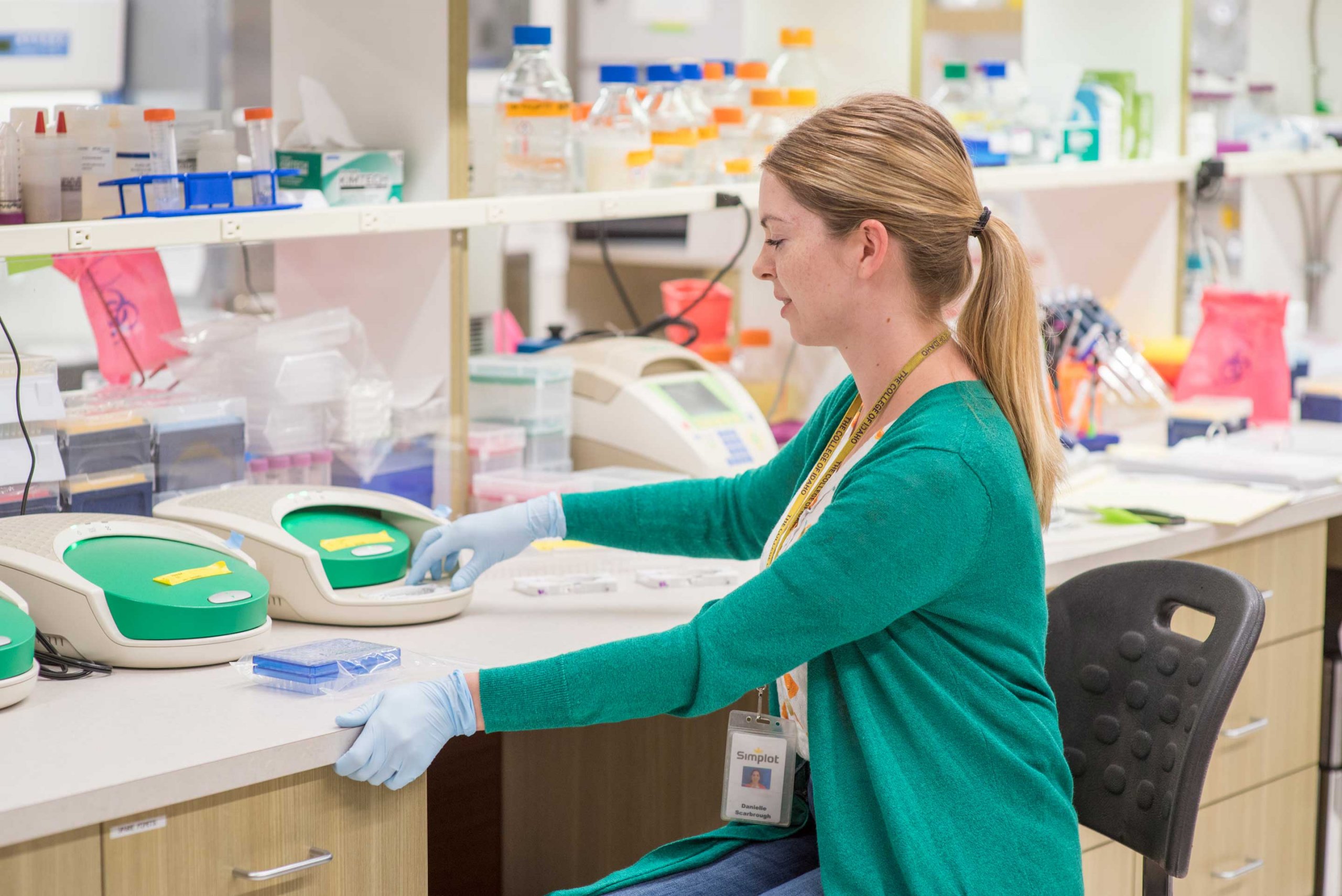 A woman wearing blue gloves in a laboratory.